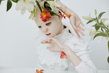 Surreal art portrait of a model with a mask and floral elements, expressing emotions of serenity and mystery, featuring gentle colors and a minimalistic background