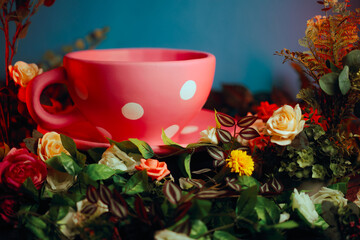 Cup of Herbal Tea Sitting in a Flowerbed Background in Nature. Lovely oversize pink mug with polka dots design  
