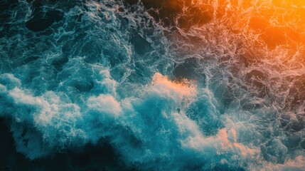 Fototapeta premium Aerial view of ocean waves illuminated by sunset colors.