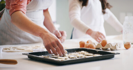 Hands, baking and mother with child in kitchen with dough for learning with cookies or biscuits. Tray, eggs and mom teaching girl kid to cook with ingredients and utensils for dessert in home.