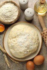 Fresh dough, ingredients and rolling pin on grey table, flat lay