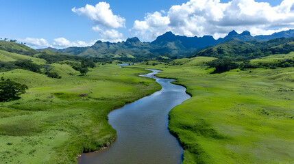 Fototapeta premium Serene river meandering through lush green valley, mountains backdrop; nature travel photography