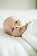 Baby, nursery and young newborn on a home bedroom in the morning calm and relax. Healthy boy, small child face and a house with a toddler ready for a nap, sleeping and rest on a duvet and blanket