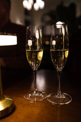 Two Glasses with a Tasting of Sparkling Wine Champagne for a Toast at an Event in a Dark Room