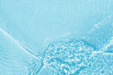 Blue water with ripples on the surface. Defocus blurred transparent blue colored clear calm water surface texture with splashes and bubbles. Water waves with shining pattern texture background.