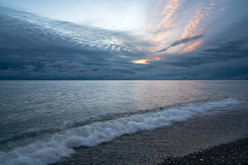 An incoming wave on the Black Sea and a pebble beach on the Sochi coast on a summer day with...