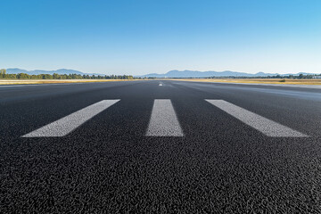 Fototapeta premium Asphalt Runway Extends to Distant Mountains under a Clear Sky