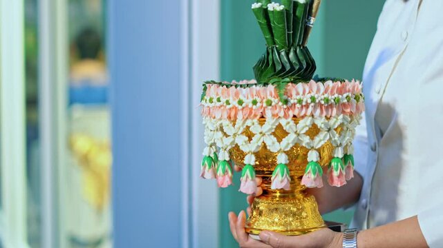 A beautifully arranged decorative offering featuring vibrant flowers and green leaves, often used in cultural and religious ceremonies. The intricate design showcases craftsmanship and serves as a mea