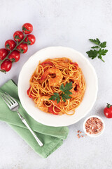 Spaghetti with shrimps, tomato sauce and parsley on white background. Top view. Italian cuisine