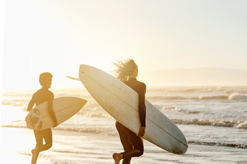 Sunset, enjoying and friends at the beach with surfboards for a hobby, waves and learning an activity. Calm, training and men in the water by the ocean for surfing, competition and sports in the sea