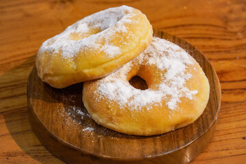 Freshly baked donuts dusted with fine sugar on a wooden table, captured on February 1, 2025. The golden-brown texture and sweet coating create an irresistible, mouthwatering treat