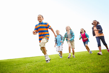 Adventure, running and group of children on grass for outdoor games, race and happy development. Diversity, energy and kids playing in field together with smile, growth and summer fun on low angle.