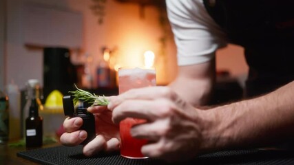 Bartender ignites rosemary for a cocktail, creating a warm, cozy atmosphere. Perfect for showcasing mixology skills in beverage commercials or bar scene enhancements.