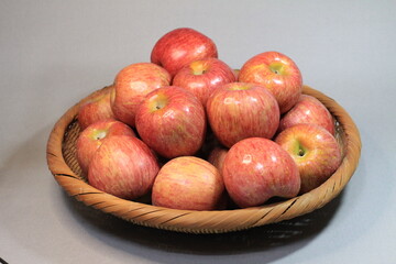 Apples in a rattan basket. This apple is shiny, fresh, and sweet. Several items were placed in the basket at once.