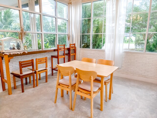 Minimalist Cafe Seating:  A simple yet elegant cafe interior with a light wood dining table and chairs arranged in a square formation, bathed in natural light streaming through large windows.