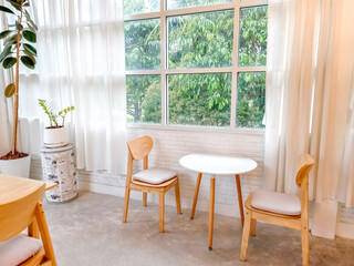 Cozy Corner:  A minimalist living space bathed in natural light, featuring a small round table with two chairs set against a backdrop of floor-to-ceiling windows.