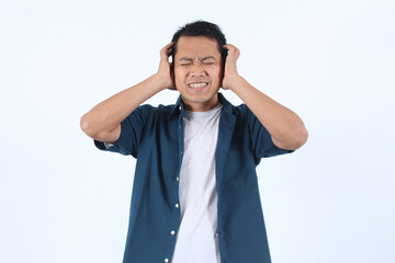 Adult Asian Man with his head down and his hands on his ears. He looks like he is in pain