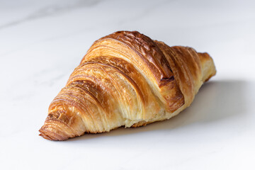 Freshly baked croissant isolated on marble background. isolated on white background. single French pastry closeup photo. buttered bread croissant on marble background. 