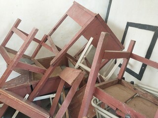 piles of broken school chairs and desks in the warehouse