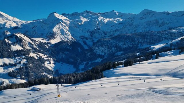 Panoramic view of the snow-covered alpine mountain range, featuring a gondola lift and skiers gliding down pristine white slopes under a bright, sunny winter sky