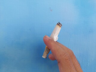 a cigarette gripped with 2 fingers