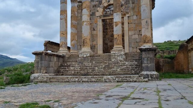 Revealing shot of the ancient Septimius Severus Temple ruins at Djemila, Algeria, framed by a dramatic cloudy sky. A captivating glimpse into history and the grandeur of this archaeological treasure