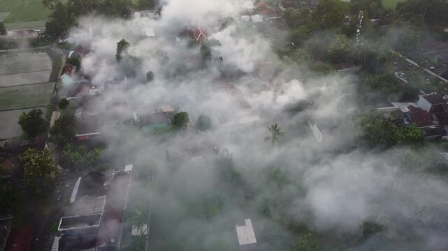 Aerial drone view of fogging to eliminate mosquito for preventing spread dengue fever and zika virus in residential areas in the morning