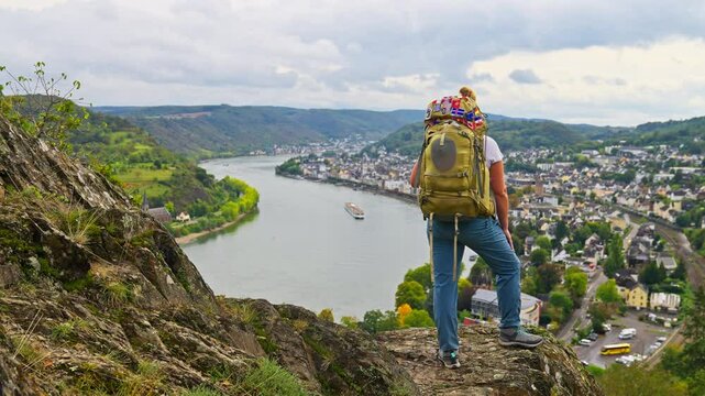 Behind woman wearing hiking gear, looking at breathtaking dramatic skyline view over the Rhine River Valley and small picturesque town, Boppard, Germany, Europe