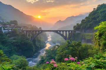 Obraz premium Serene Sunset Over Bridge and River Surrounded by Lush Green Hills and Vibrant Flowers in Tranquil Landscape Scene