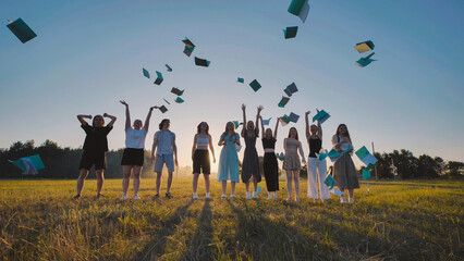 Happy students celebrate the end of the school year by throwing their notebooks in the air in a...