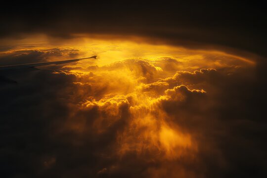 Aerial view from an airplane window showing the wing and golden clouds at sunrise.