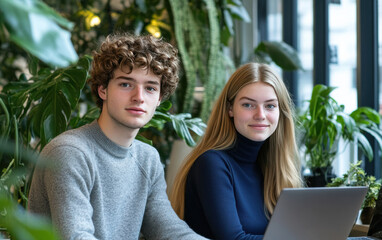 Fototapeta premium Surrounded by greenery, two focused professionals work at a table in a naturally lit office, creating a harmonious work environment.