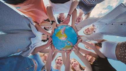Group of smiling students holding a globe, promoting global citizenship, environmental awareness, and international friendship