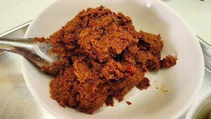 Curry paste for Thai cooking. Spicy chili paste in white bowl on stainless steel surface.