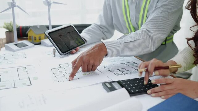 Close up of hands working brainstorming and measuring for cost estimating on paperworks and floor plan drawings about design wind energy, wind tubine.