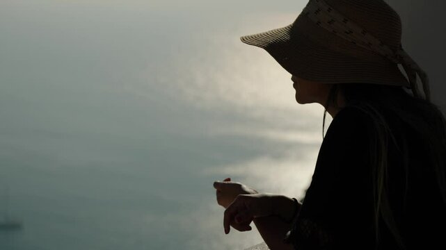 A Side View of a Woman in a Brimmed Hat, Gazing Out at the Coast of Portugal - Close Up