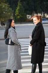 Women enjoy conversation on a street in an autumn afternoon
