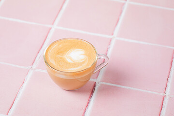A cup of cappuccino coffee on pink tile background