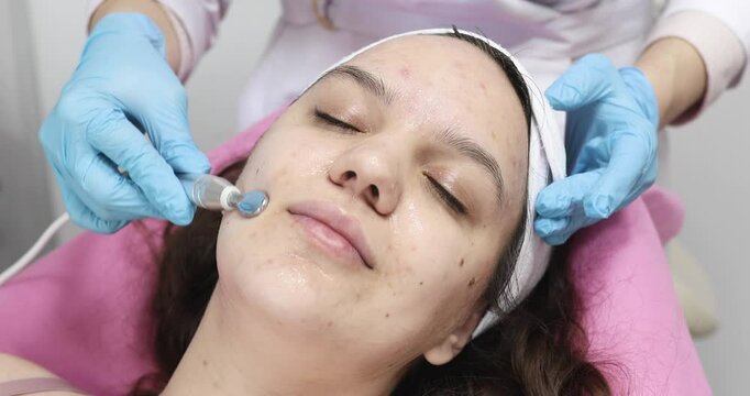 People, beauty, spa, cosmetology and technology concept - Cosmetologist makes the procedure microcurrent therapy of the facial skin of a beautiful, young woman in a beauty salon