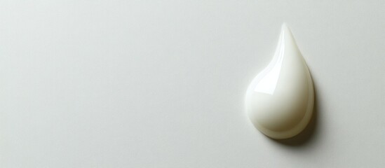 Fototapeta premium White cream droplet on a smooth light gray background with copy space for text placement