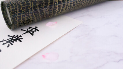 春の訪れを告げる、卒業証書と桜の花びらと卒業証筒