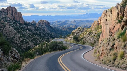 Scenic winding mountain road offering stunning panoramic views of rocky landscapes and distant horizons under a cloudy sky.