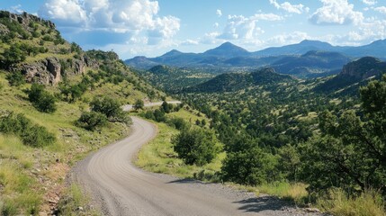 Naklejka premium Scenic winding mountain road surrounded by lush greenery and breathtaking views under a clear blue sky