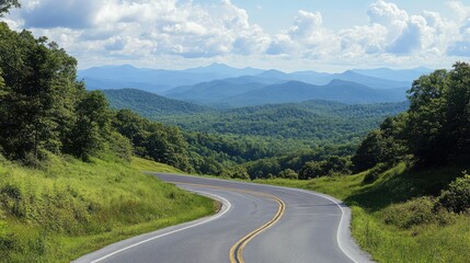 Fototapeta premium Scenic winding road through lush green hills with distant mountains and blue sky creating a picturesque nature landscape.