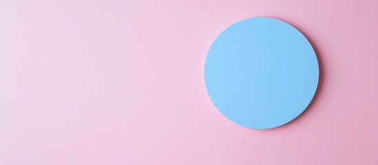 Obraz premium Blue circular object on a soft pink background with ample negative space for text placement