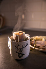 Cup of coffee in a drip bag on the table in the kitchen