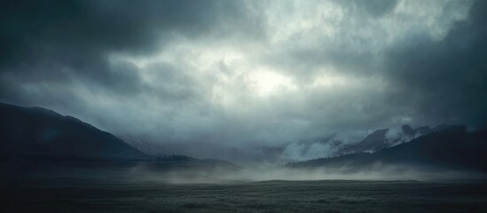 Fototapeta premium Moody landscape with dark clouds over a lake and mist rising from the water reflecting a dramatic sky Copy Space