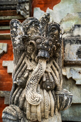 Masterfully carved temple protector statue displays detailed facial features and ornamental designs, weathered by time yet maintaining its fierce presence