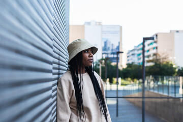 Horizontal shot of serious self confident woman with dreadlocks hairstyle dressed in fashionable...