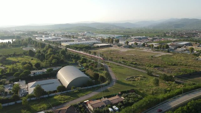 A stunning aerial shot of an Italian Freccia Rossa high-speed train speeding along the tracks, showcasing its sleek design and rapid movement through the landscape with precision and power.